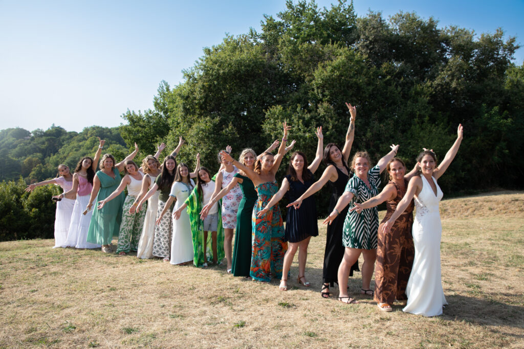 Photo de groupe originale de la mariée et ses invitées en file indienne dans un champ, mariage en Gironde.