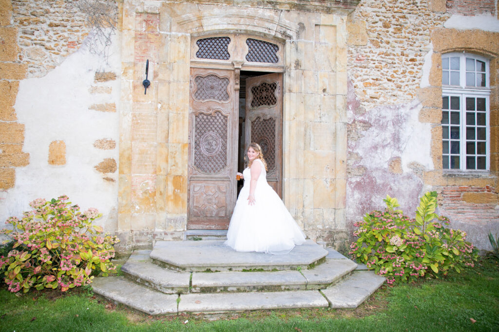 Mariée seule posant devant la porte sculptée d'un château historique en Gironde.